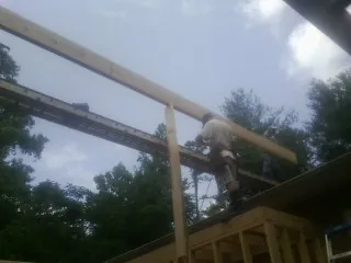 Carpenter setting a ridge beam over a new addition frame — Ice Dam Removal by Roofing Brothers in Waterman