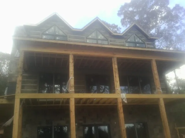 Dormers and porch framing on a large log home under construction — Roof Coating work by our crew in Waterman