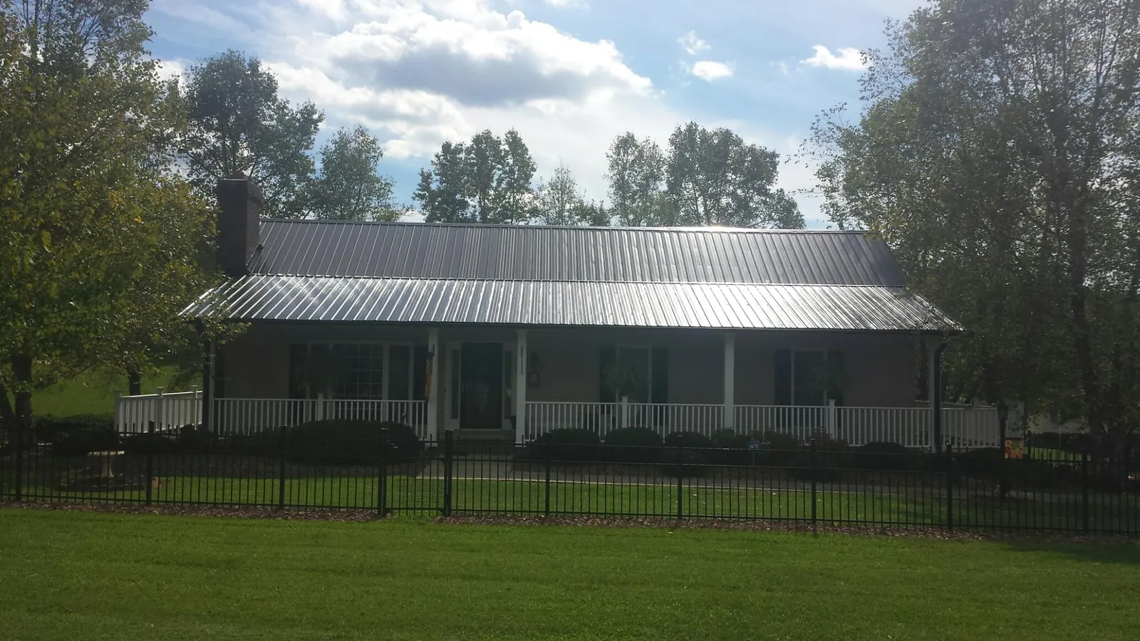 Gray metal roof on a brick ranch with a full width front porch — Gutter Guard Installation work by our crew in Waterman