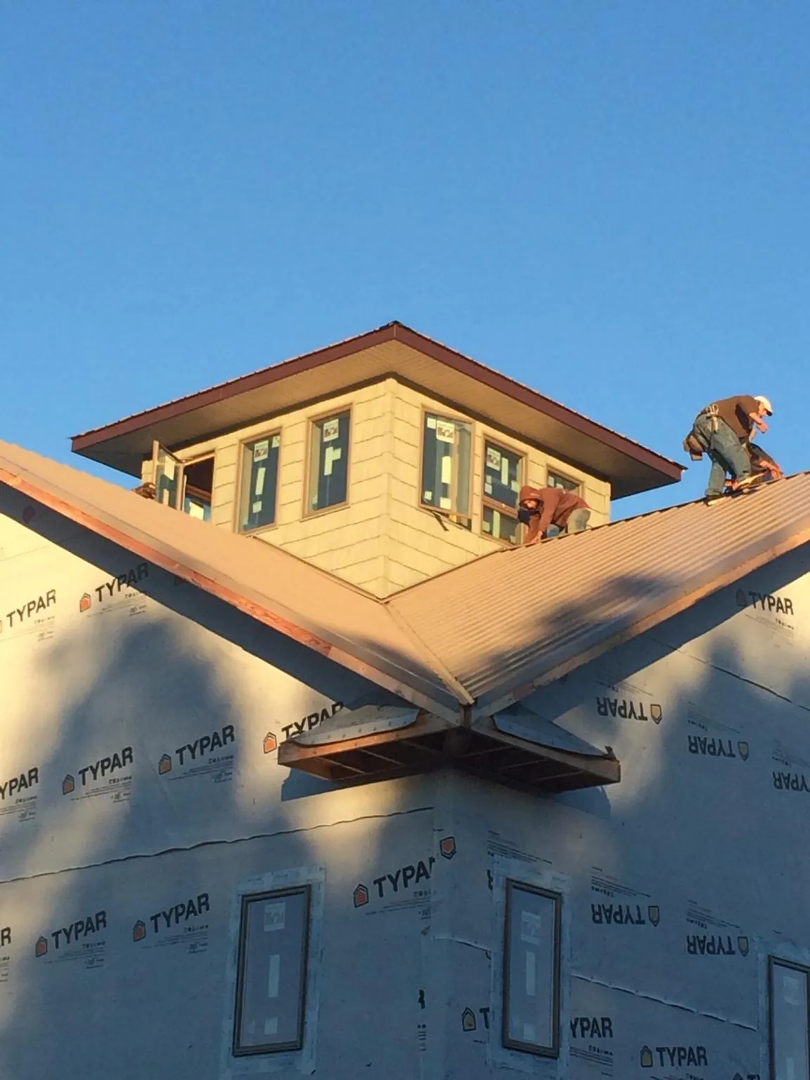 Roofers working around a rooftop cupola on a new metal roof at sunset — Roof Waterproofing in Waterman by Roofing Brothers